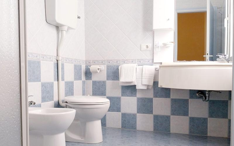 Gemütliches Badezimmer mit blauen Fliesen und reflektierendem Spiegel.
